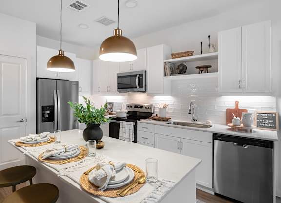 A modern kitchen with a white countertop and stainless steel appliances.
