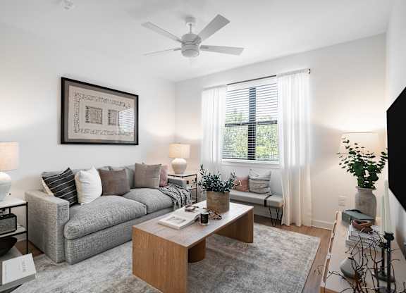 A living room with a grey couch, a wooden coffee table, and a ceiling fan.