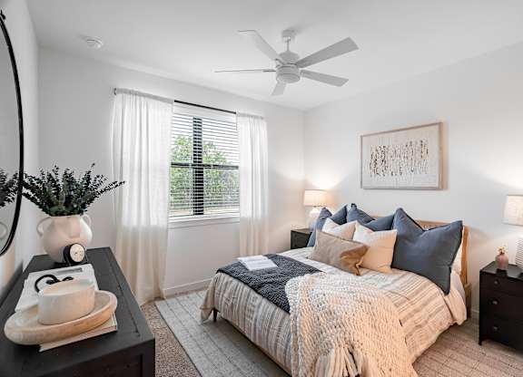 A bedroom with a bed, nightstands, and a ceiling fan.