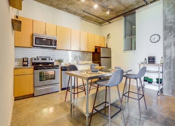 Open kitchen with island seating and industrial details at 1221 Broadway Lofts Apartments, San Antonio
