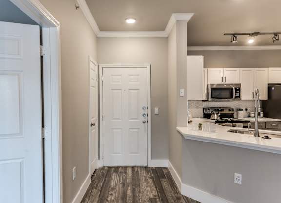 A kitchen with white cabinets and a white door at Rosemary Apartments, Texas, 77384