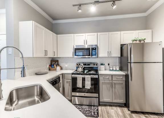 A modern kitchen with a stainless steel refrigerator, microwave, and oven at Rosemary Apartments, Conroe, TX