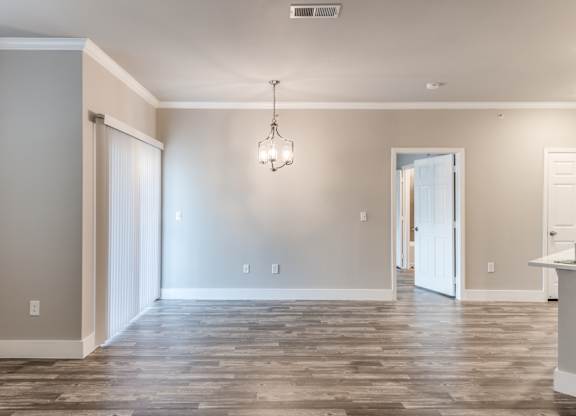 A room with a wooden floor and a chandelier hanging from the ceiling at Rosemary Apartments, Conroe