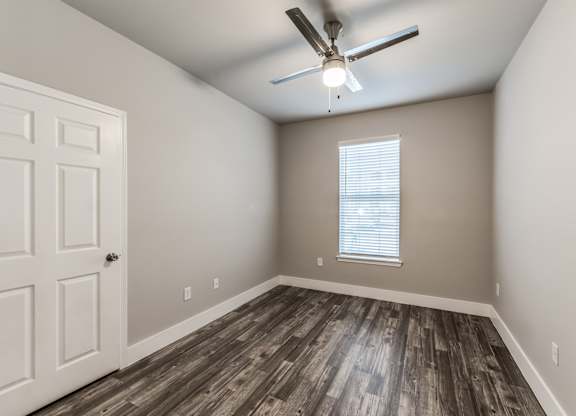 A room with a ceiling fan and wooden flooring at Rosemary Apartments, Texas