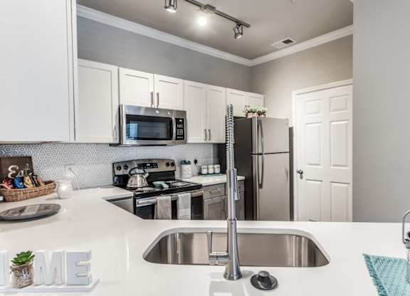 A kitchen with a stove, sink, and refrigerator at Rosemary Apartments, Texas