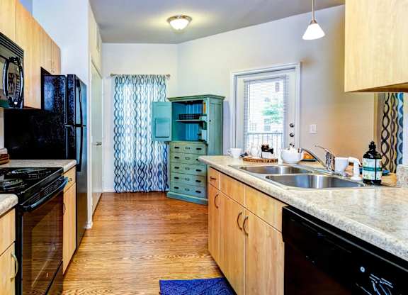 a kitchen with a black stove top oven next to a sink and a refrigerator at Villa Espada Apartments, Texas, 78221