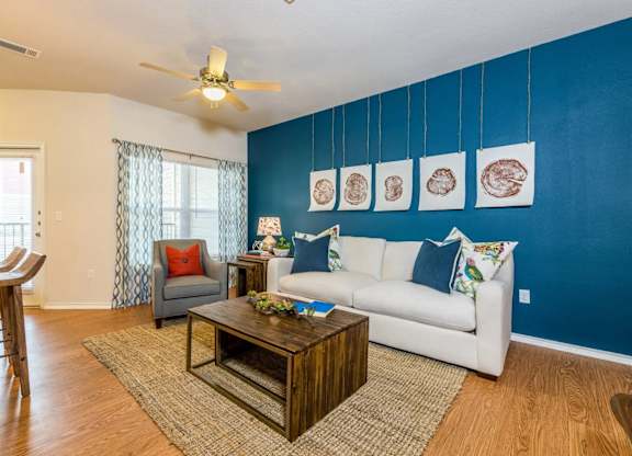 a living room with a white couch and a blue accent wall at Villa Espada Apartments, Texas, 78221