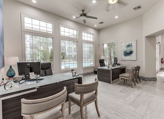 A well-lit office with a desk, chairs, and a ceiling fan at Rosemary Apartments, Conroe