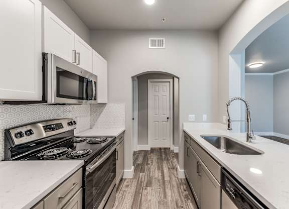 A kitchen with a stove, microwave, and sink at Rosemary Apartments, Conroe, Texas