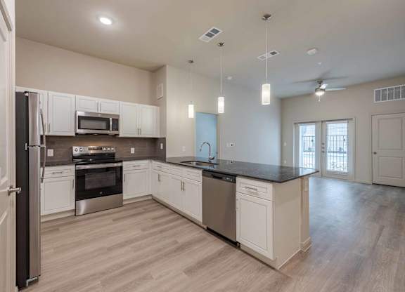 Open concept kitchen with island and pendant lighting at Emilia Apartments, Boerne, Texas