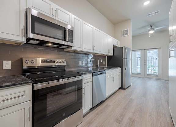 Kitchen with white cabinets and gray countertops at Emilia Apartments, Texas, 78006