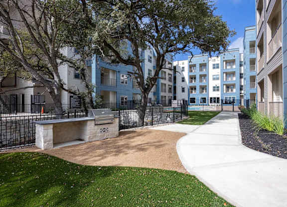 Outdoor courtyard with walking path and mature trees at Emilia Apartments, Boerne, 78006
