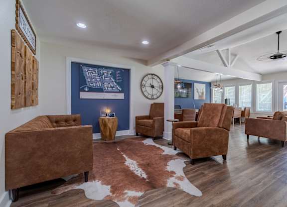 A living room with brown furniture and a cowhide rug.