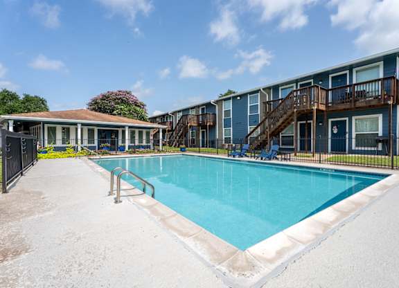 A swimming pool surrounded by a fence and a building in the background.