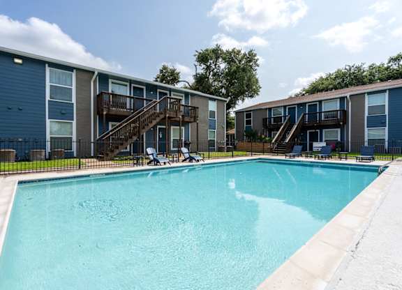 A swimming pool in front of a building with a balcony.