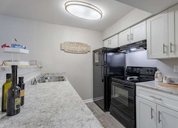 A kitchen with a black refrigerator and white cabinets.