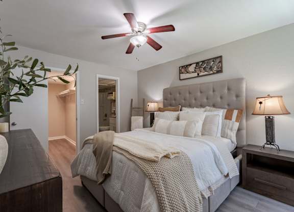 A bedroom with a large bed and a ceiling fan.