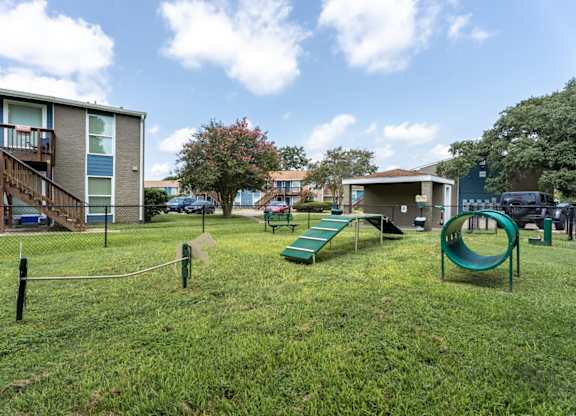 A playground with a green slide and a play area in front of apartment buildings.