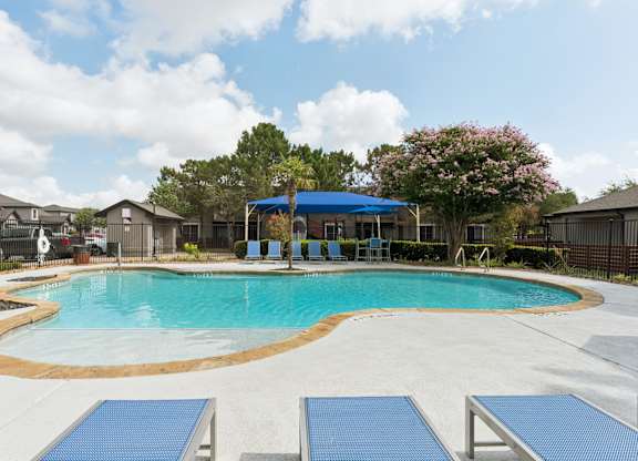 A swimming pool with a blue tiled edge and a small pavilion with a blue roof.