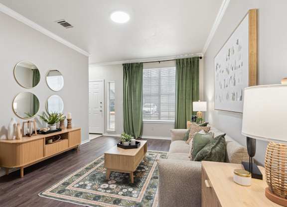 A living room with a rug, a couch, a table, and a mirror on the wall.