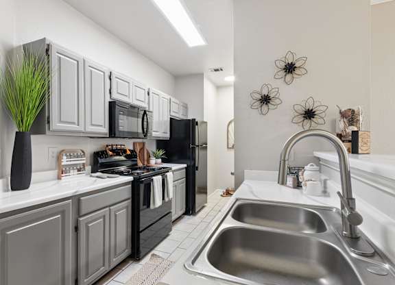 A modern kitchen with a black refrigerator and stove, and a stainless steel sink.
