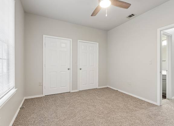 A room with a ceiling fan and three doors.