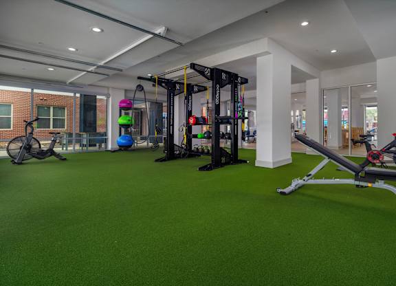 A gym with a green floor and various exercise equipment.