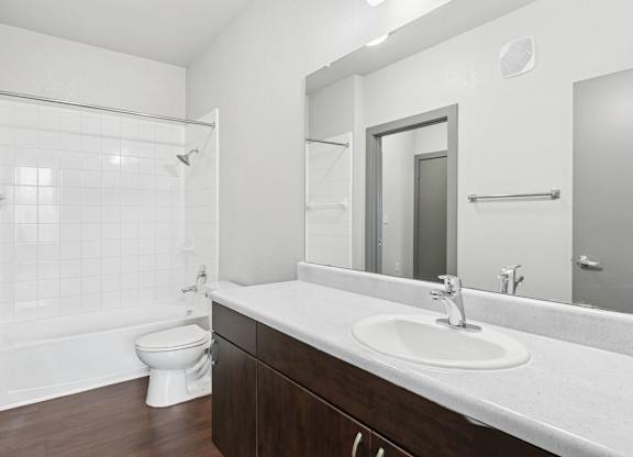A white bathroom with a toilet, sink, and mirror.