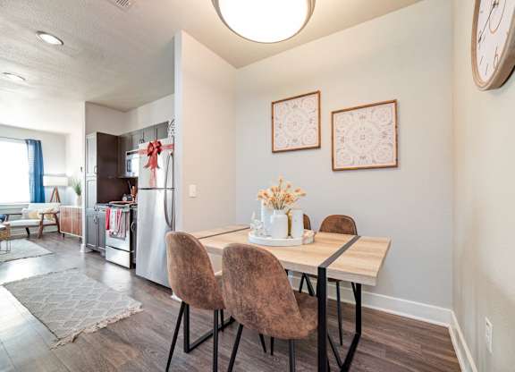 a dining area with a table and chairs and a kitchen in the background at The Landings at Brooks City-Base, San Antonio, TX, 78235