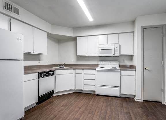 a kitchen with white cabinets and white appliances  at Rosillo Creek Apartments, San Antonio, TX