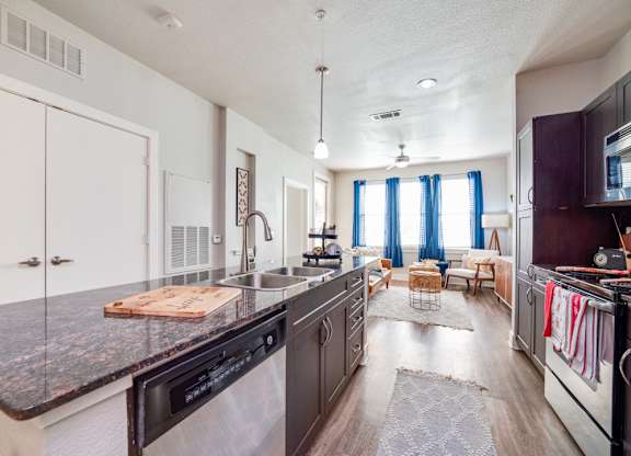 a kitchen with a large island and a living room in the background at The Landings at Brooks City-Base, San Antonio, TX, 78235