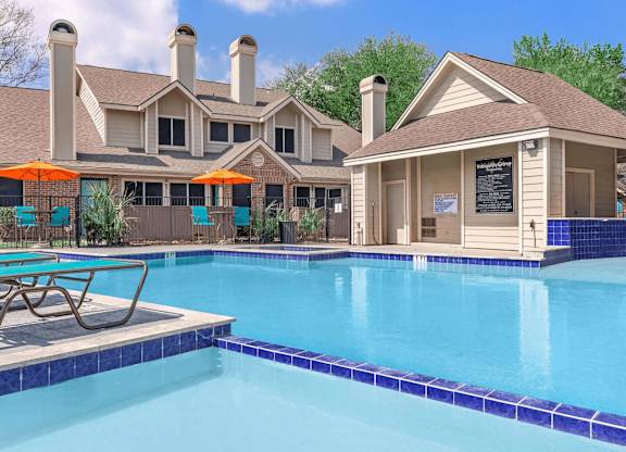 a swimming pool with chairs and a house in the background at Tranquility Grove, Texas 77090