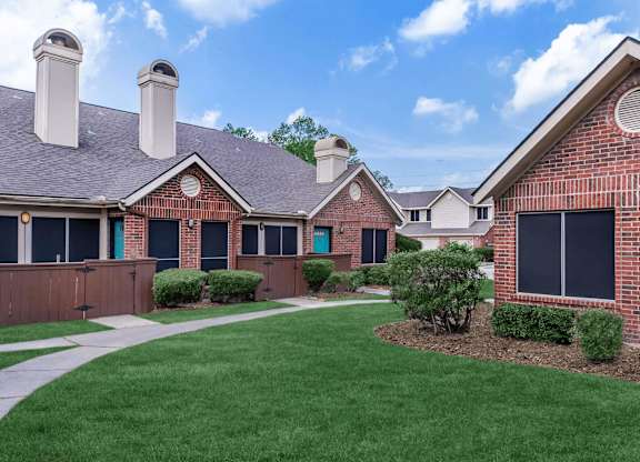a yard in front of a brick house with a blue door at Tranquility Grove, Houston, TX 77090