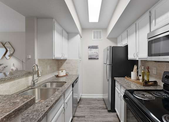 Galley kitchen with granite countertops and white cabinets at Monarch Medical Center Apartments, Houston, 77054