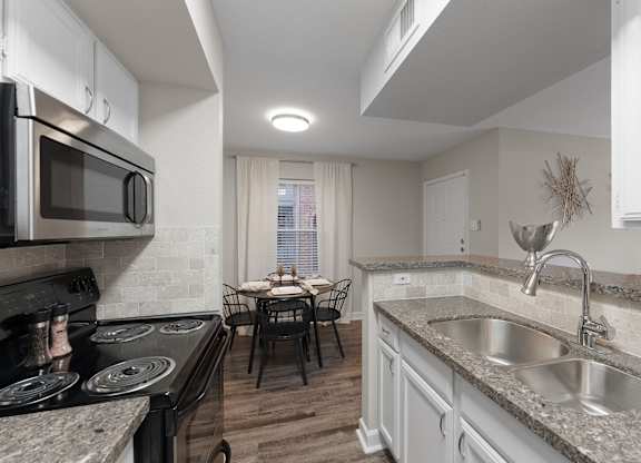 Modern kitchen with stainless steel appliances and dining area at Monarch Medical Center Apartments, Houston, Texas