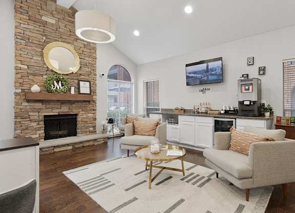 Living room with stone fireplace and coffee station at Monarch Medical Center Apartments, Texas