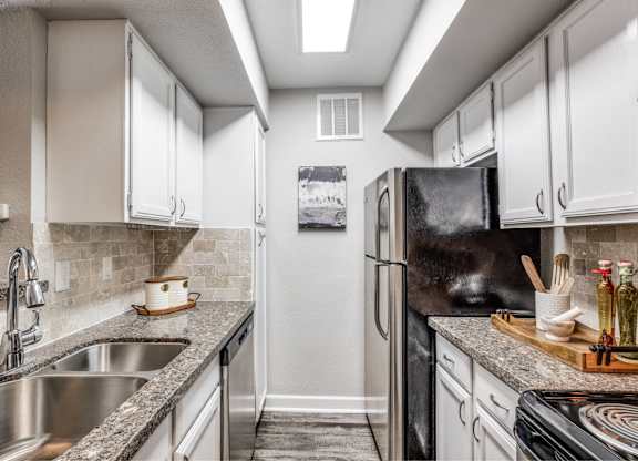 Galley kitchen with white cabinetry and granite counters at Monarch Medical Center Apartments, Houston, 77054