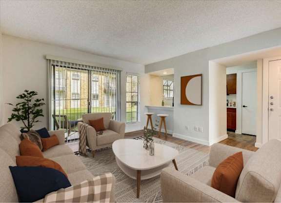 Bright living room with neutral furnishings at The Courtyard Apartments, Garland