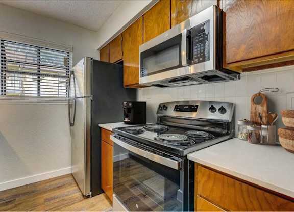 Kitchen with stainless steel appliances and wood cabinets at The Courtyard Apartments, Texas, 75044