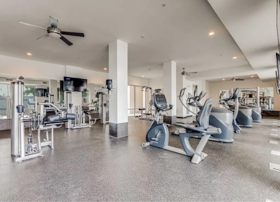 A spacious gym with a variety of equipment including treadmills, stationary bikes, and weight machines.