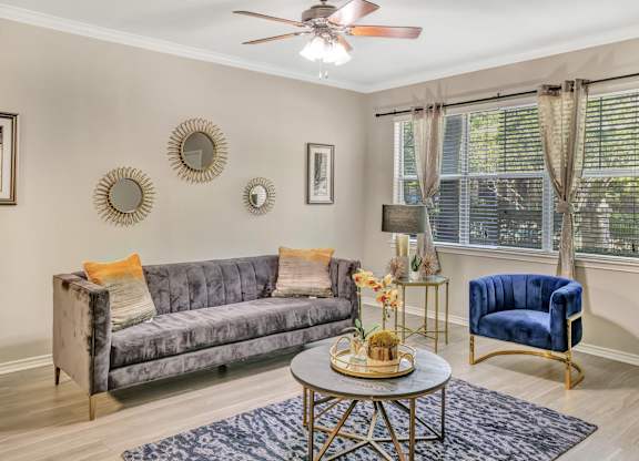 A living room with a grey couch, a blue chair, and a table with a vase of flowers on it.