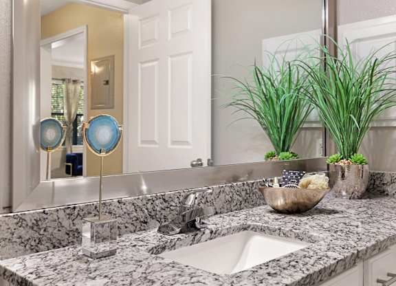 A bathroom with a marble counter top and a white sink.