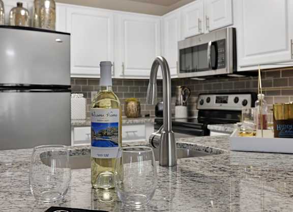 A bottle of white wine is on a kitchen counter.