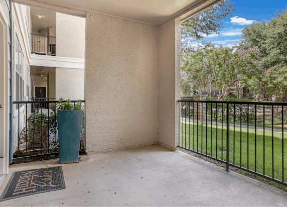A balcony with a black railing and a green trash can.
