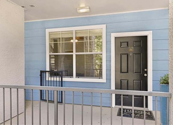 A blue house with a black door and a window with a black frame.