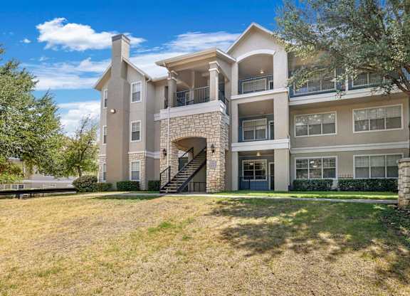 A large two-story apartment building with a stone staircase leading to the entrance.