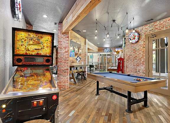 A room with a pool table and a pinball machine.