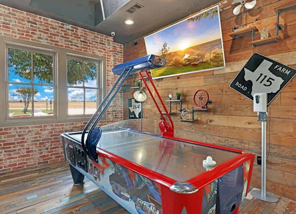 A red air hockey table in a room with a brick wall.
