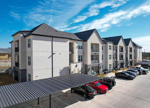 a row of apartment buildings with cars parked in front of them at The Fitzroy San Marcos, Texas