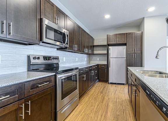 a kitchen with wood cabinets and stainless steel appliances at The Fitzroy San Marcos, Texas